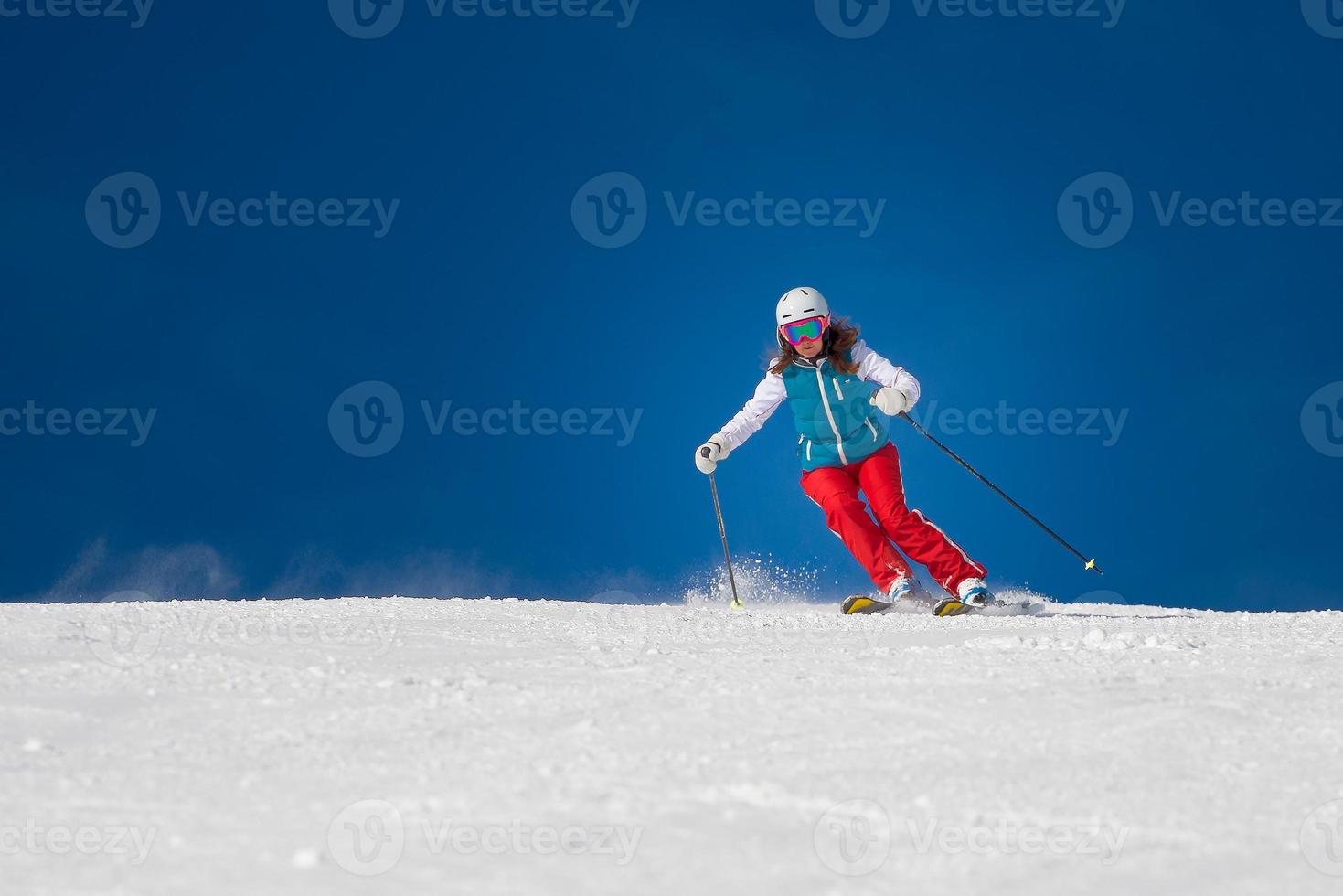 kvinnlig skidåkare skidåkning nedförsbacke under solig dag foto