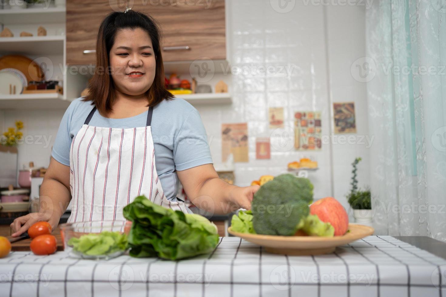 asiatisk gravid lära sig på vilket sätt till laga mat friska måltider från de internet i kök, fett kvinnor förbereda en vegetabiliska sallad för diet mat och tappa bort vikt. begrepp av friska äter foto