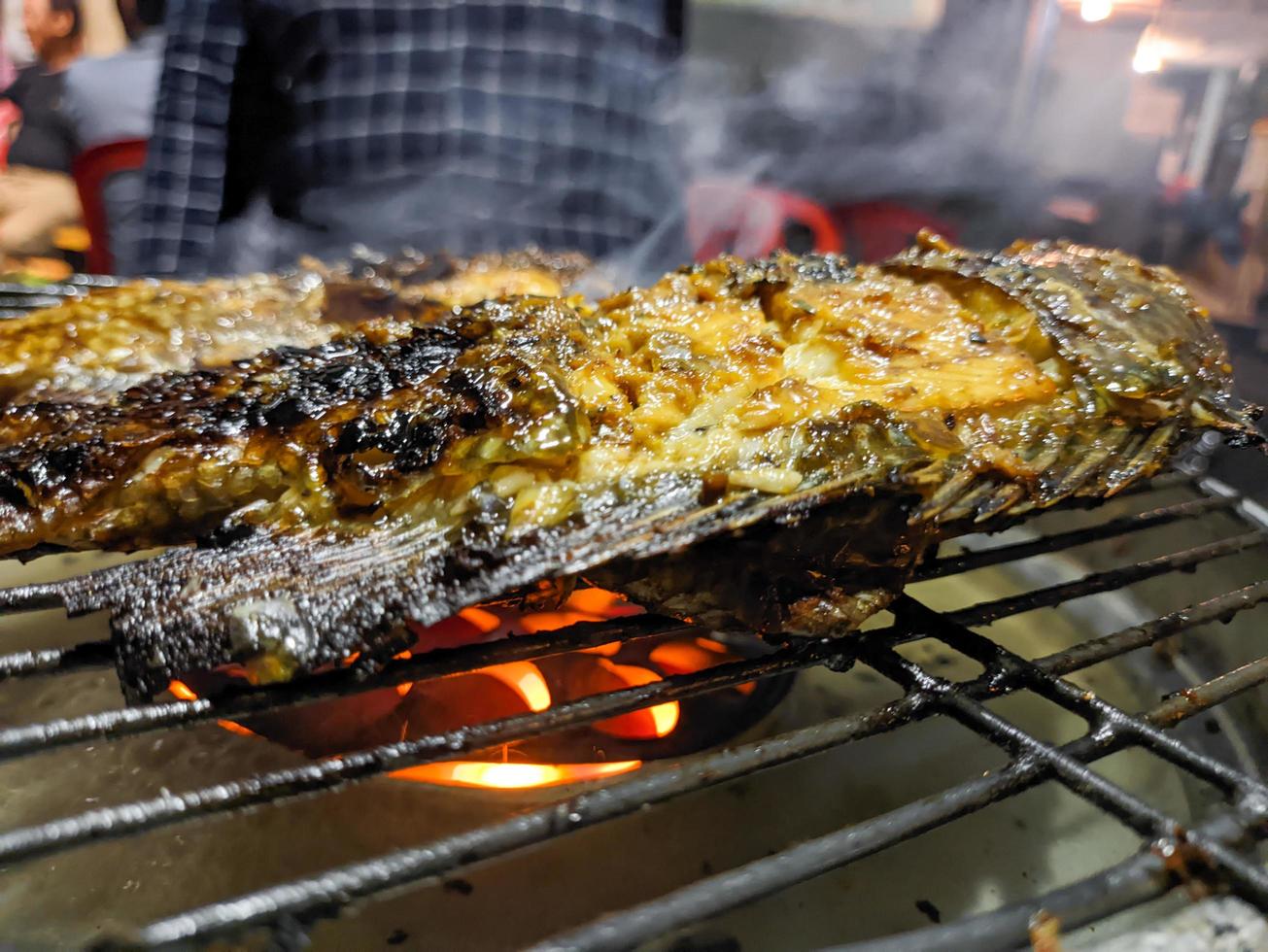 en stänga upp av fisk varelse grillad med en flammande brand. för mat tapet eller bakgrund. Nej människor foto