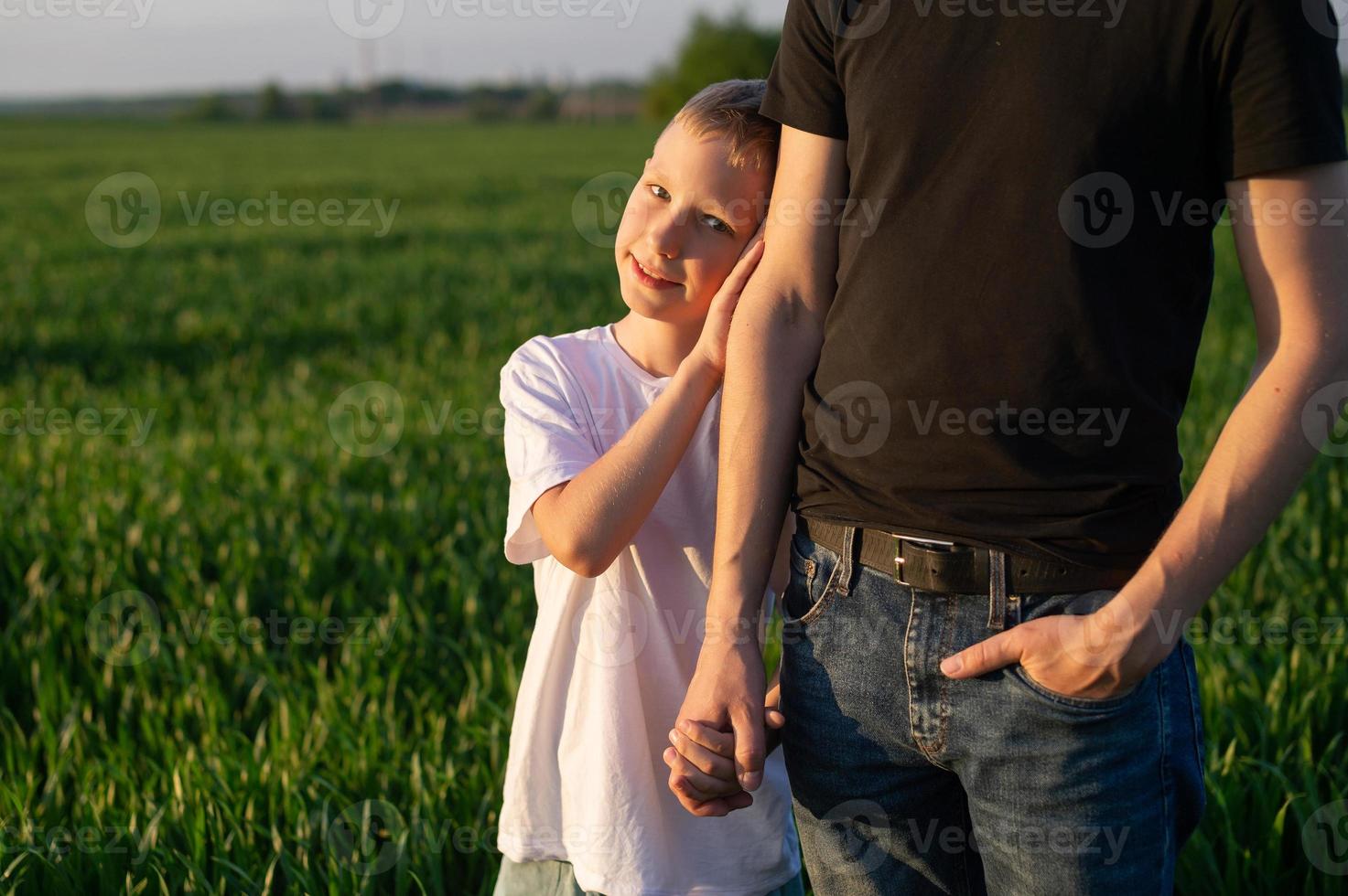 en söt barn innehar hans fars hand och myser upp till henne. natur promenad foto