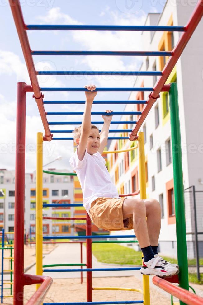 en Tonårs pojke är engagerad på horisontell barer nära de skola foto