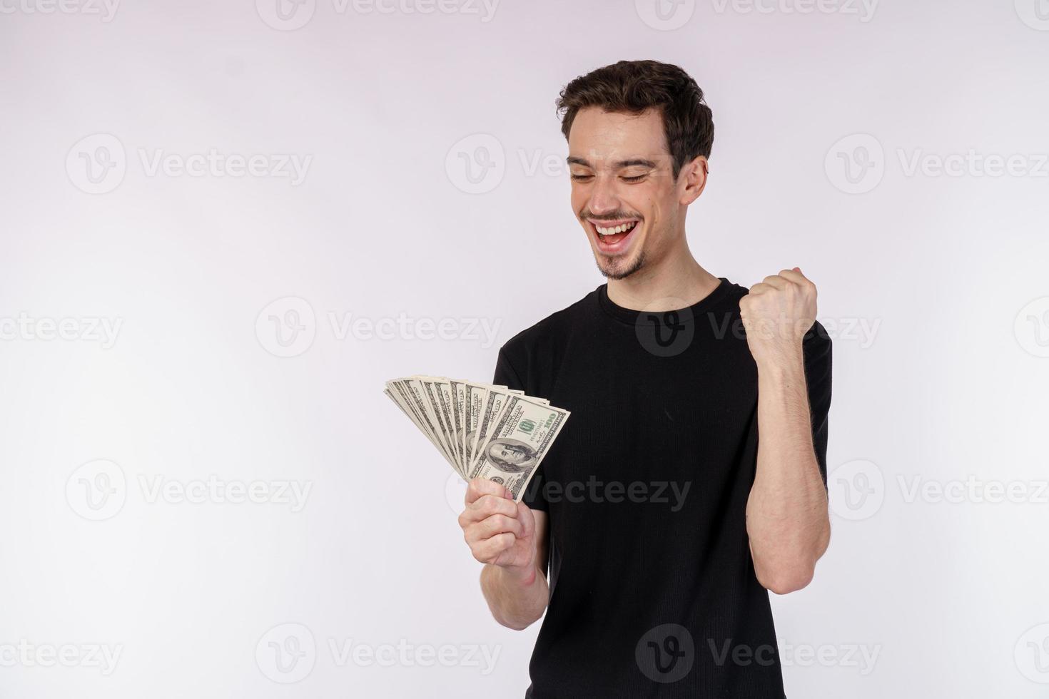 porträtt av en glad man innehav dollar räkningar och håller på med vinnare gest knäppning näve över vit bakgrund foto