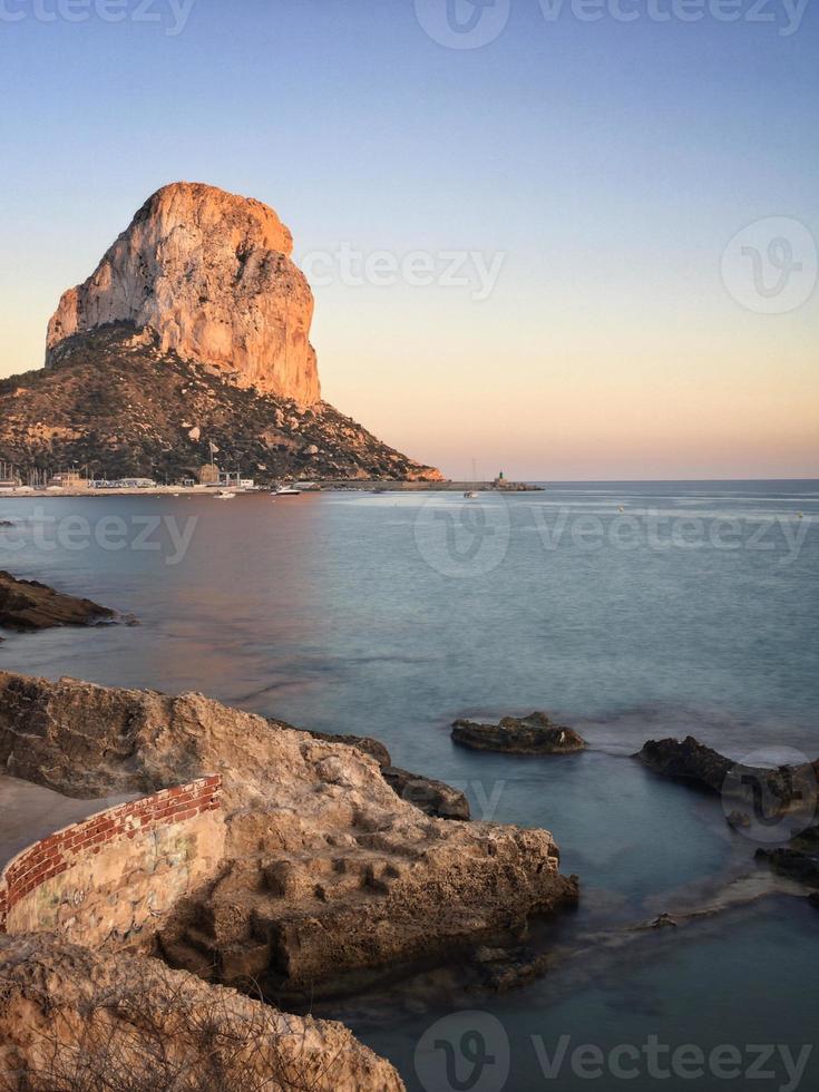 medelhavsstrand vid solnedgången med penonen i bakgrunden i calpe, alicante foto