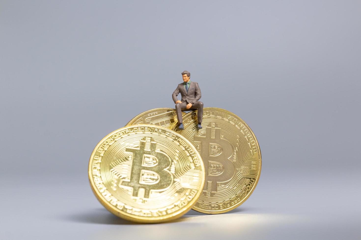 miniatyr affärsman sitter på bitcoin mynt, framtida investering koncept foto