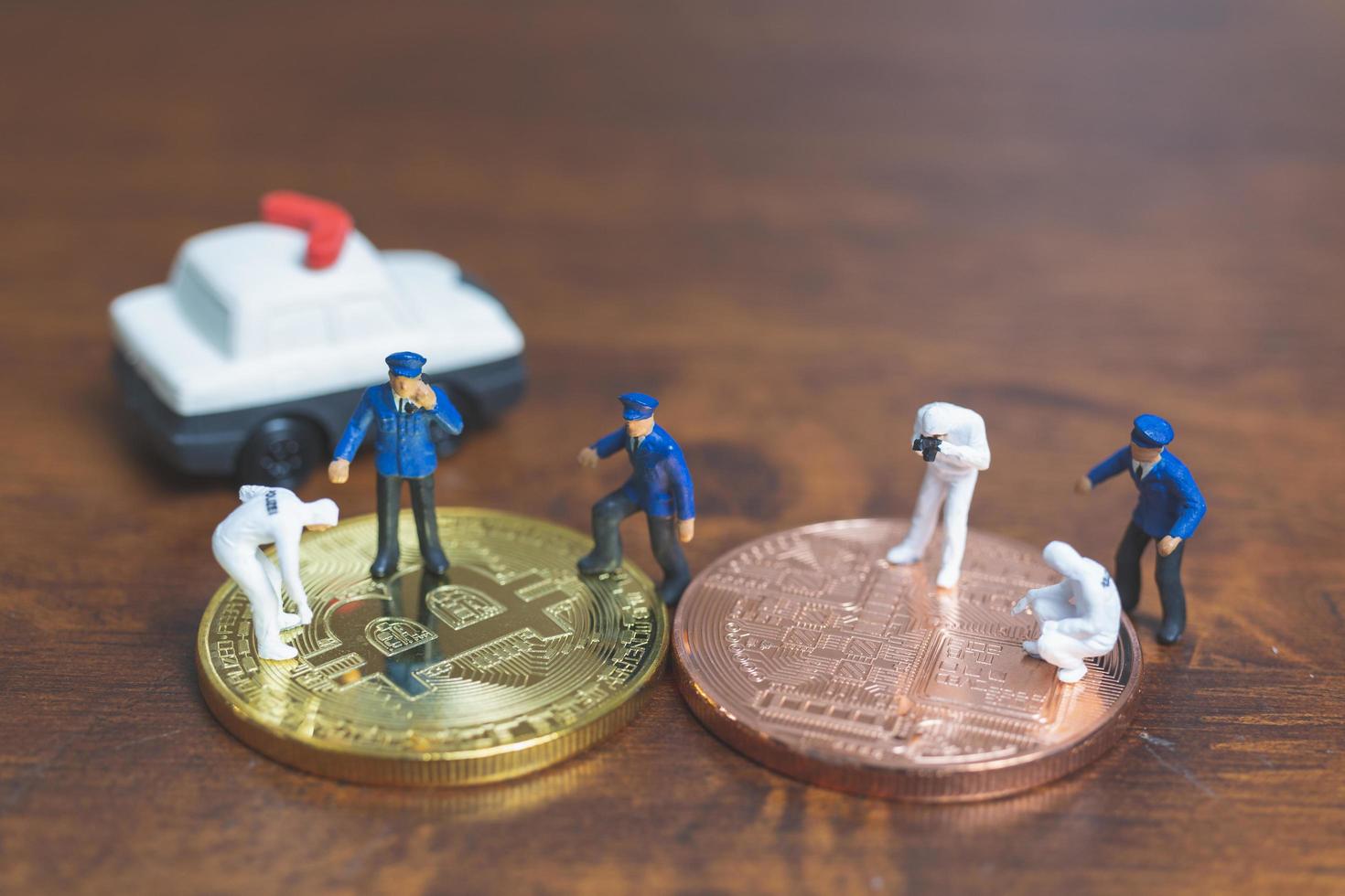 miniatyrpolis och detektiver som står framför bitcoin-kryptokurrency, cyberbrottskoncept foto