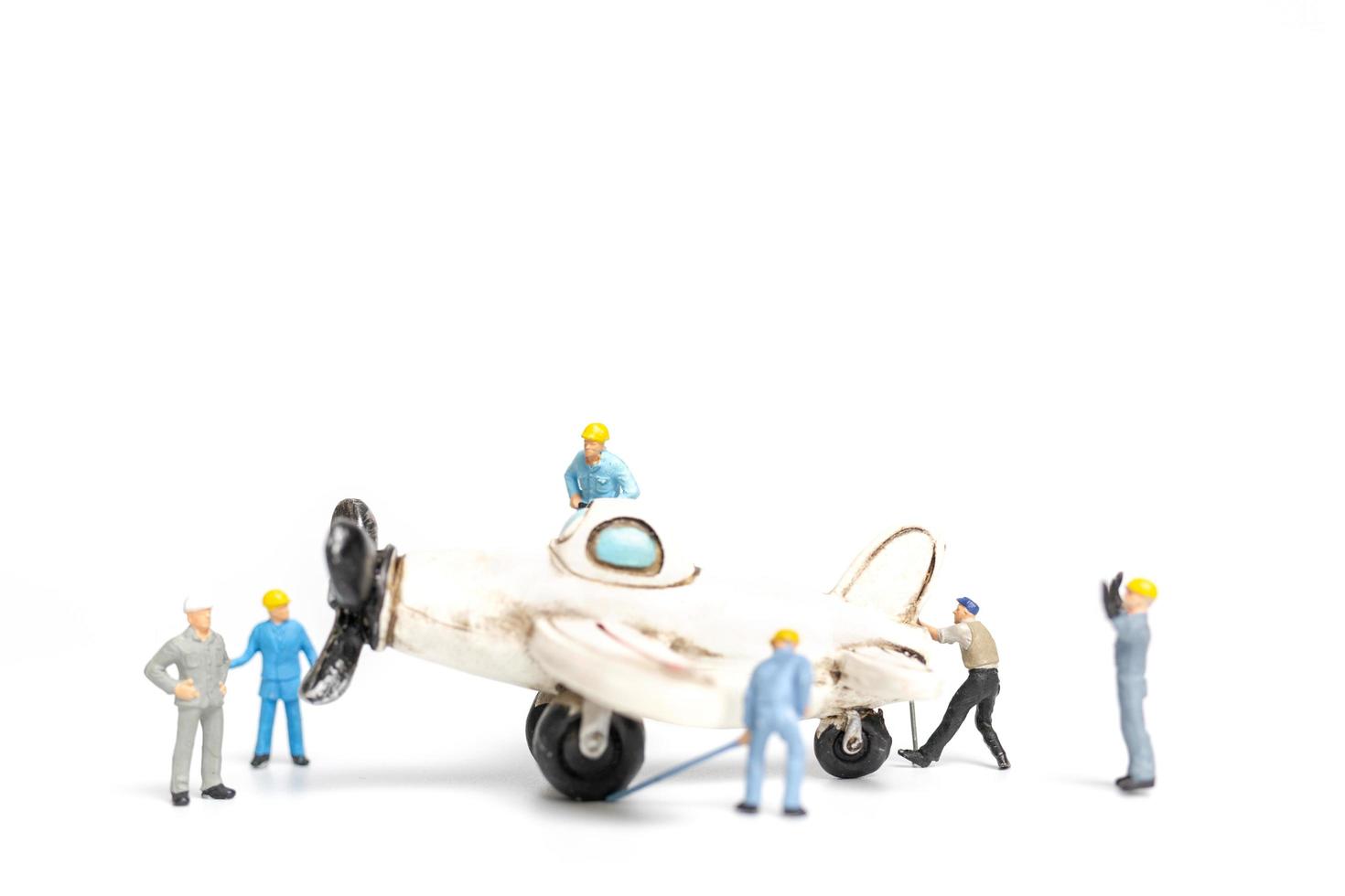miniatyrarbetare som reparerar ett leksaksflygplan på en vit bakgrund foto