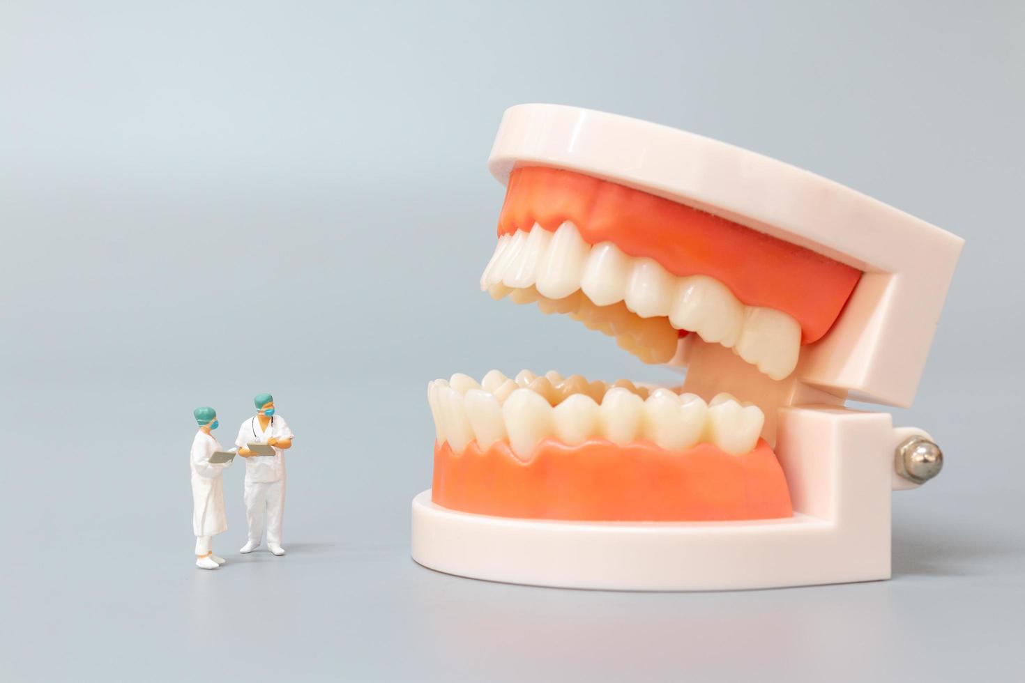 miniatyr tandläkare reparera mänskliga tänder med tandkött och emalj, hälsa och medicinska koncept foto