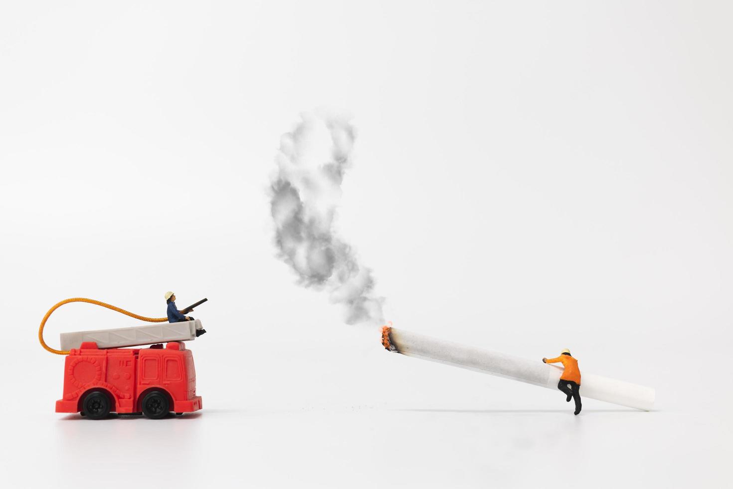 miniatyr brandmän och cigaretter på en vit bakgrund, hälsosamt koncept foto