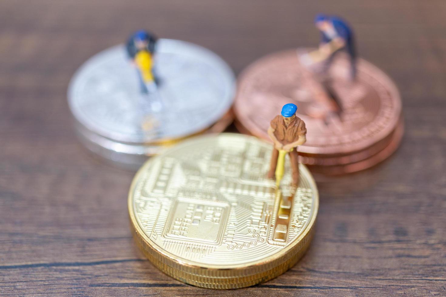 miniatyrarbetare som gör bitcoin-kryptovaluta på träbakgrund foto