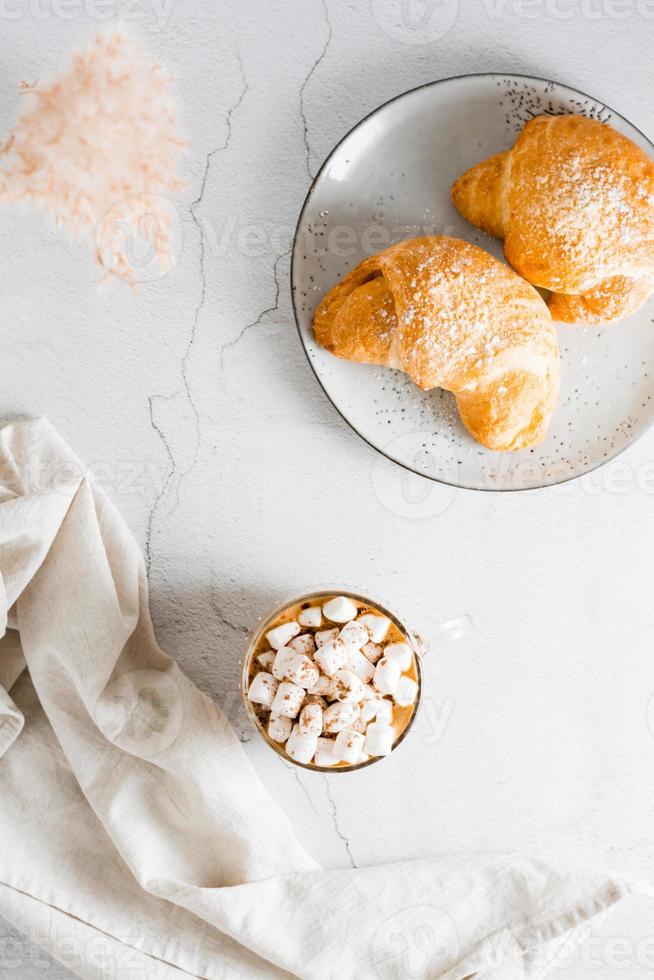 utsökt kaffe med marshmallows och croissanter på plattor på de tabell. livsstil hemlagad mellanmål. topp och vertikal se foto
