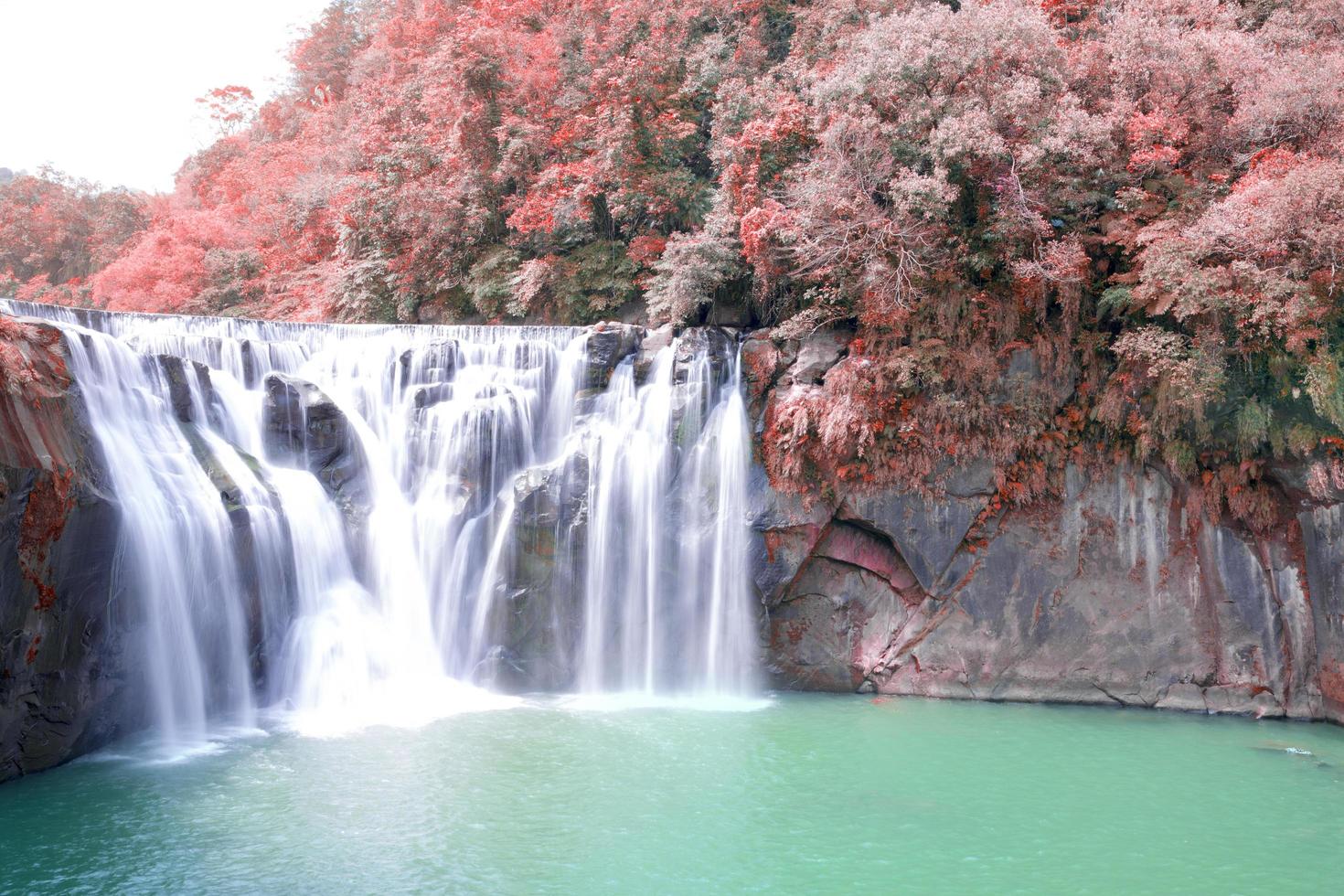 vattenfall nära röda höstträd foto