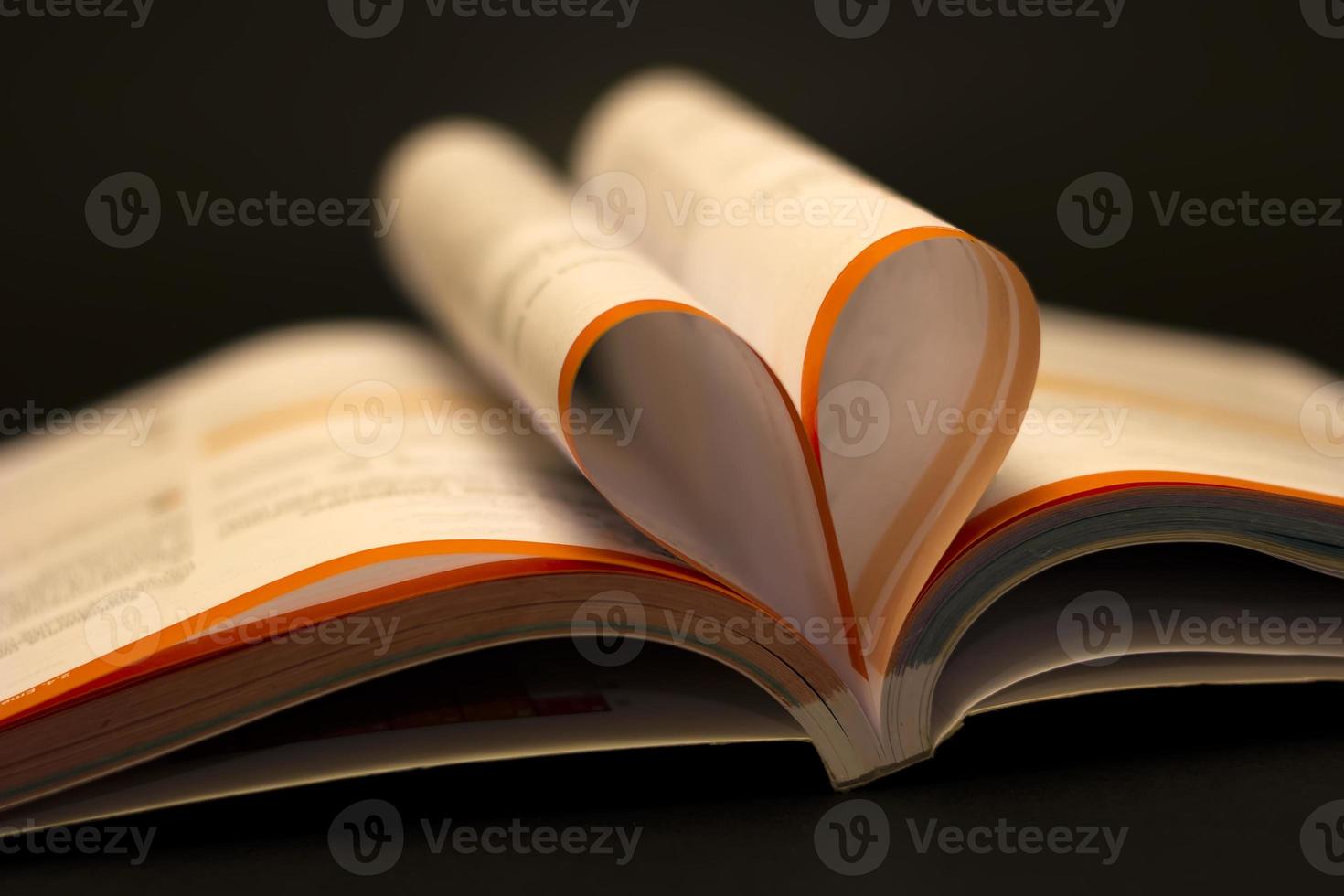 kärlek till läsa en bok begrepp. öppen bok med hjärta form sida på svart tabell. utbildning bakgrund, tillbaka till skola begrepp. foto