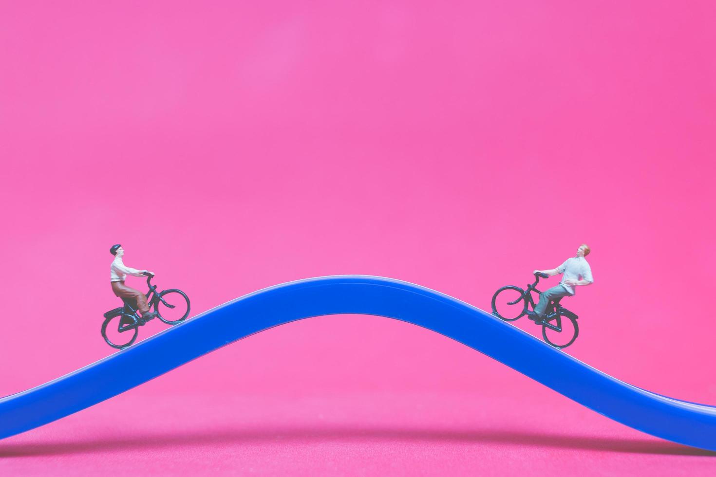 miniatyrresenärer med cyklar på en blå bro på en rosa bakgrund foto