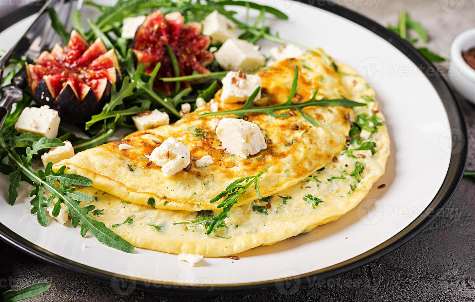 omelett med fetaost ost, persilja och sallad med fikon, arugula på vit tallrik. frittata - italiensk omelett. foto