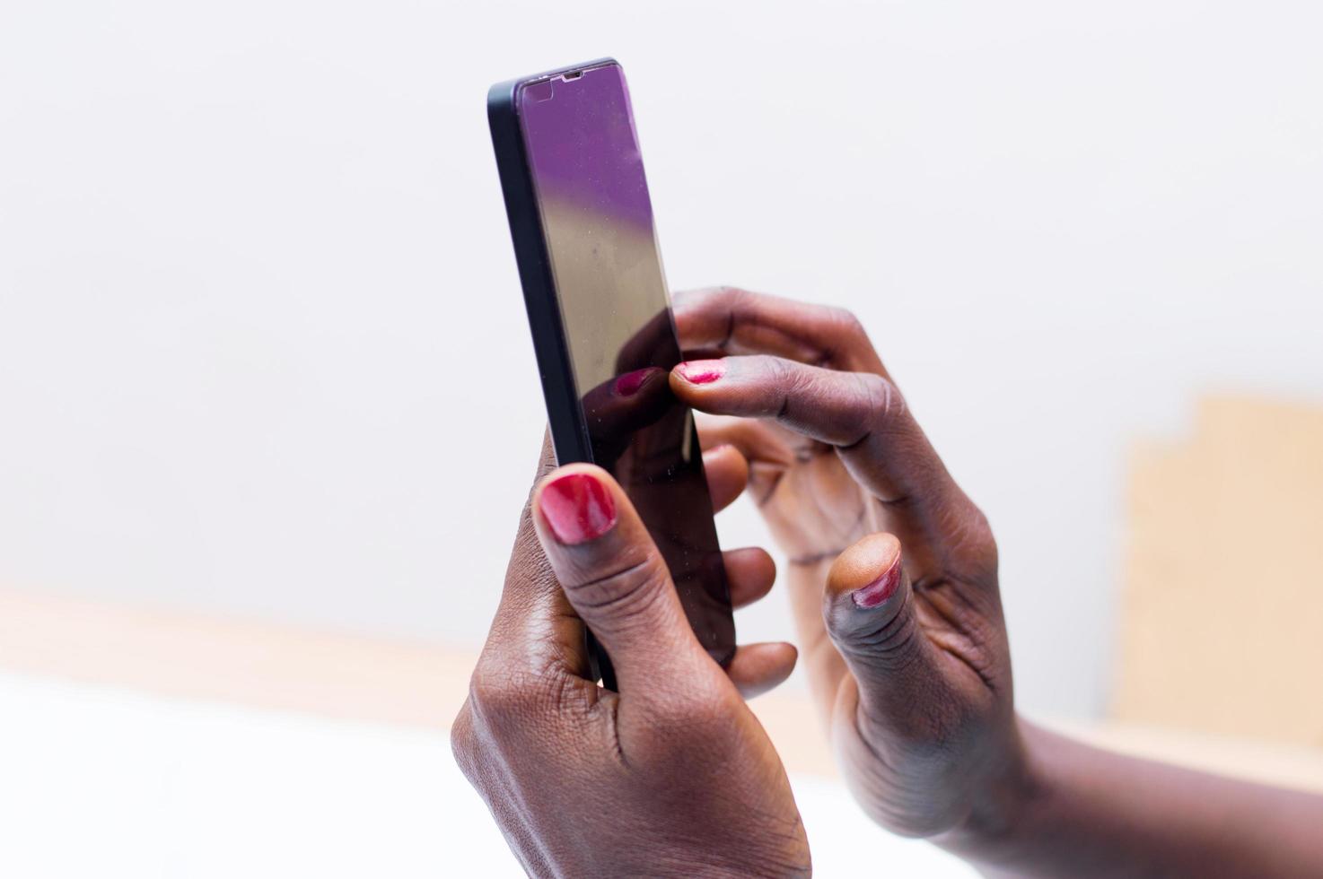 kvinnans händer som håller en mobiltelefon foto