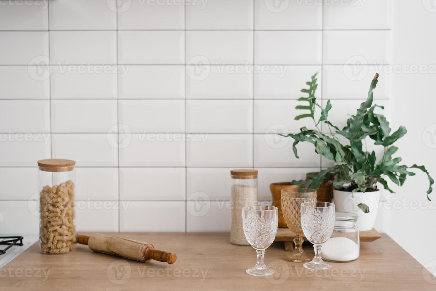 en glas burk med pasta, glasögon, en rullande stift och en krukväxt stå i de ljus kök. kök redskap, scandinavian stil foto