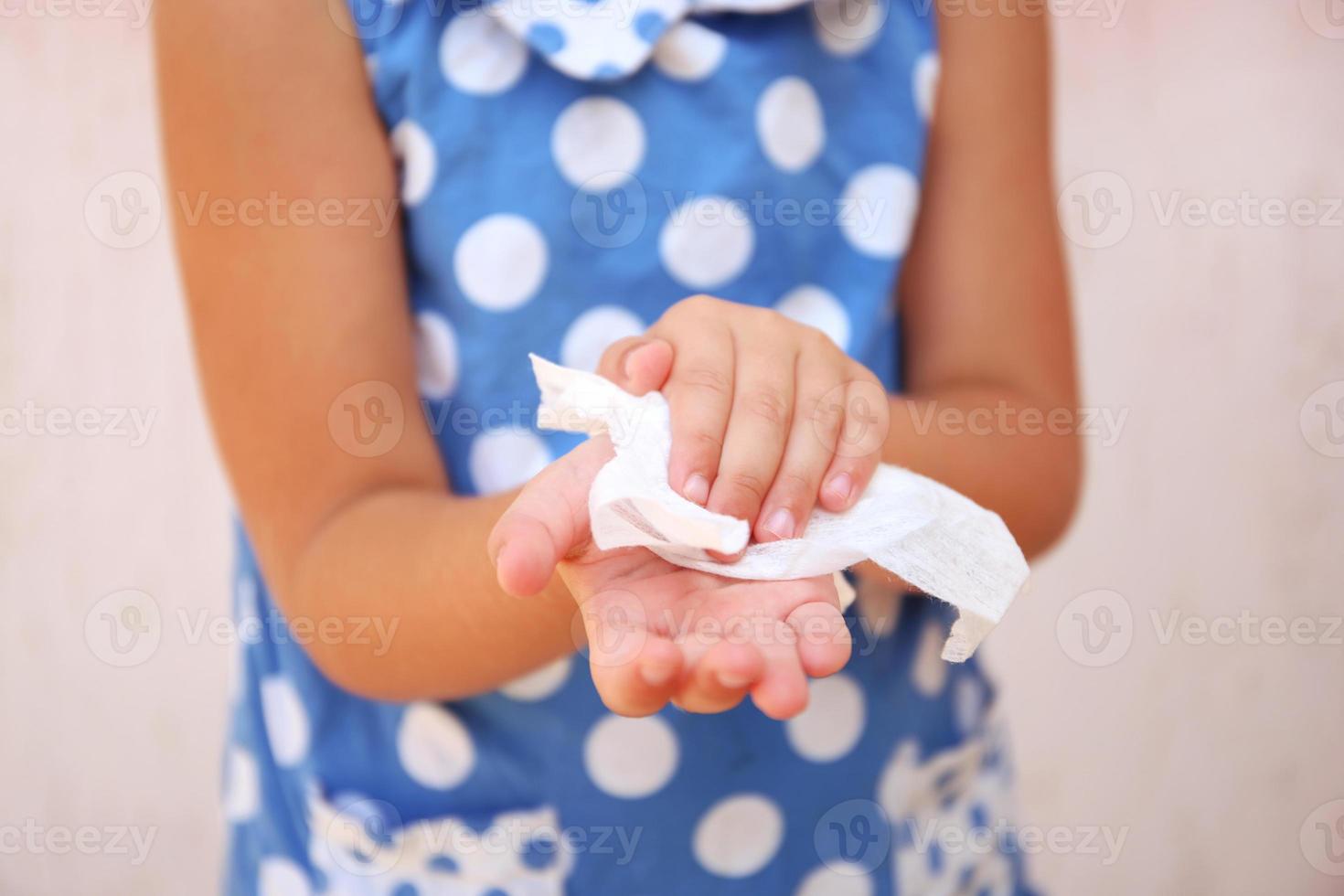 barn våtservetter hans händer med fuktig trasa. foto