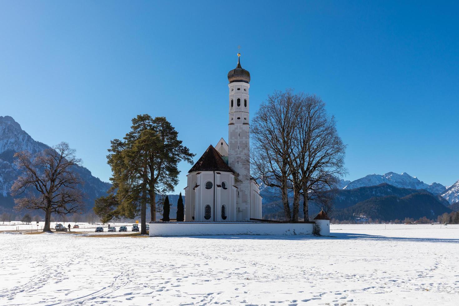 kyrka i de snö med en muntains och en blå himmel foto