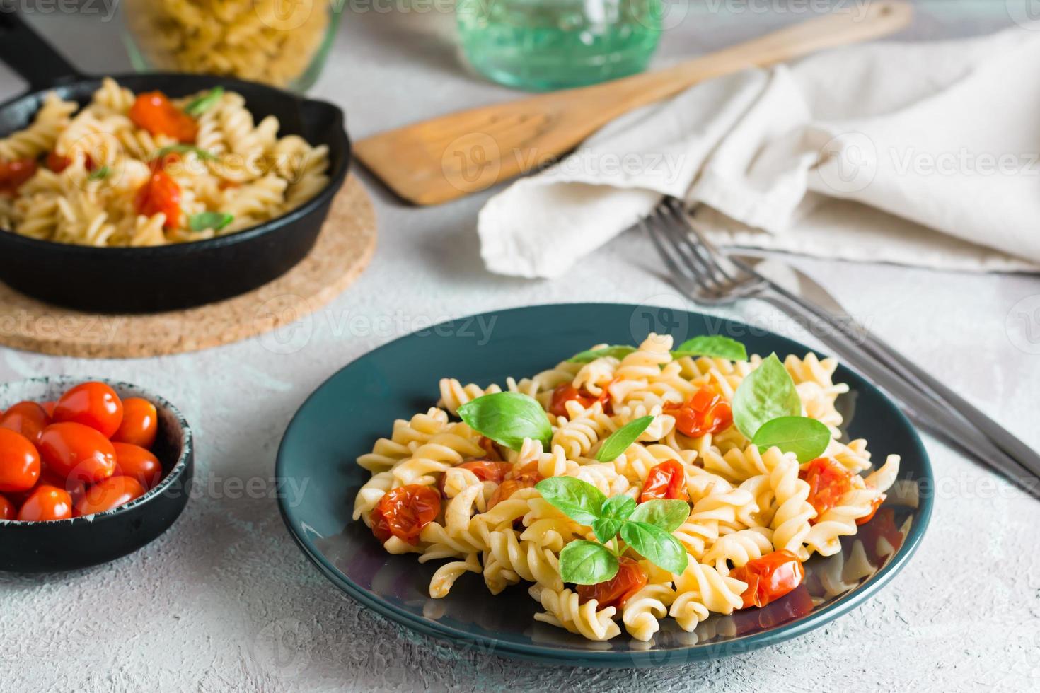 redo till äta pasta med tomater och basilika på en tallrik och Ingredienser på de tabell. medelhavs kök. foto