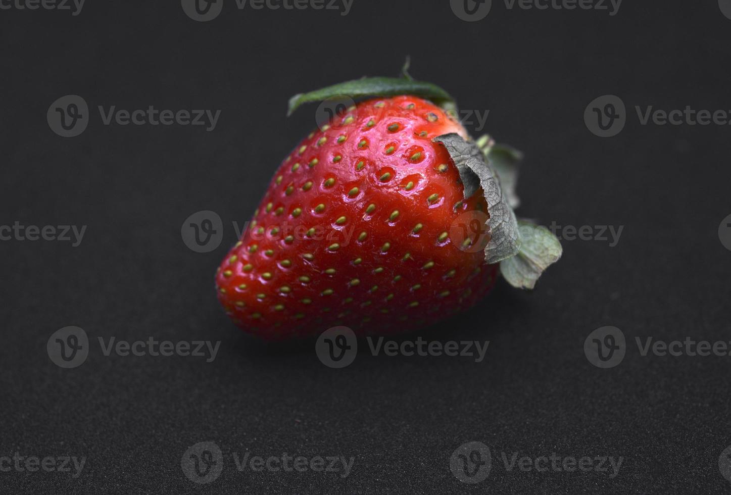 utsökt stor röd jordgubbar på en svart bakgrund. röd bär. bär victoria. foto