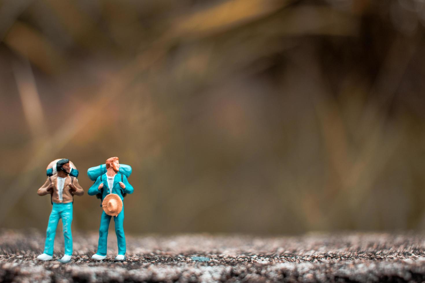 miniatyrbackpackers som står på ett betonggolv med en bokeh-naturbakgrund foto