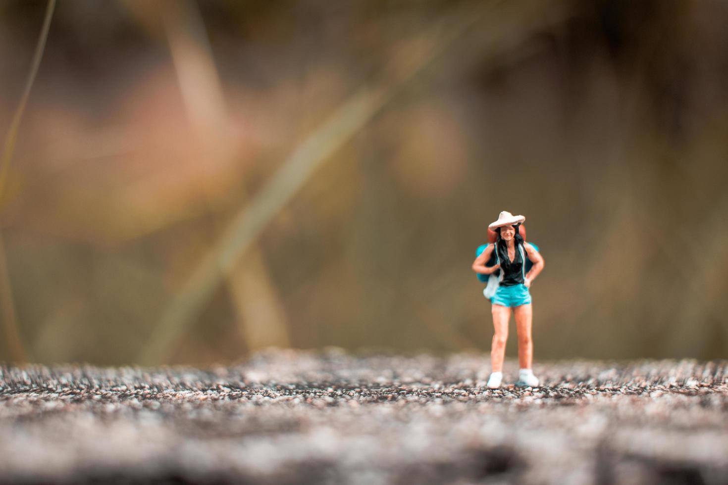 miniatyr backpacker stående på betongväggen med naturlig bakgrund foto