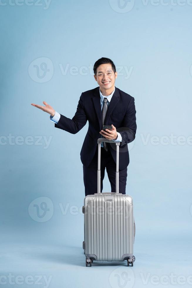 porträtt av asiatisk affärsman bär en kostym och dragande en resväska foto