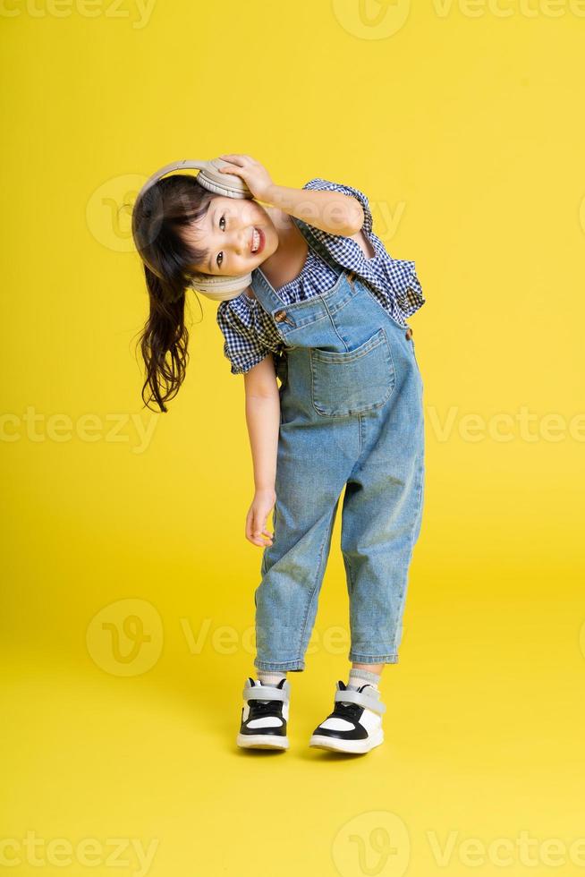 full kropp bild av skön asiatisk bebis flicka på gul bakgrund foto