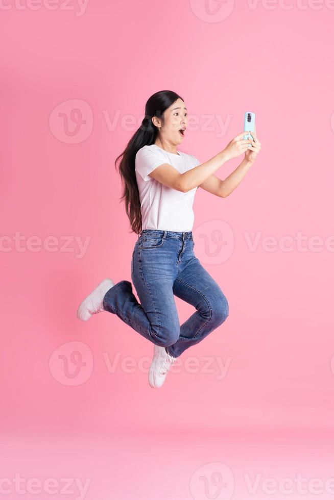 full kropp bild av asiatisk flicka Framställ på rosa bakgrund foto