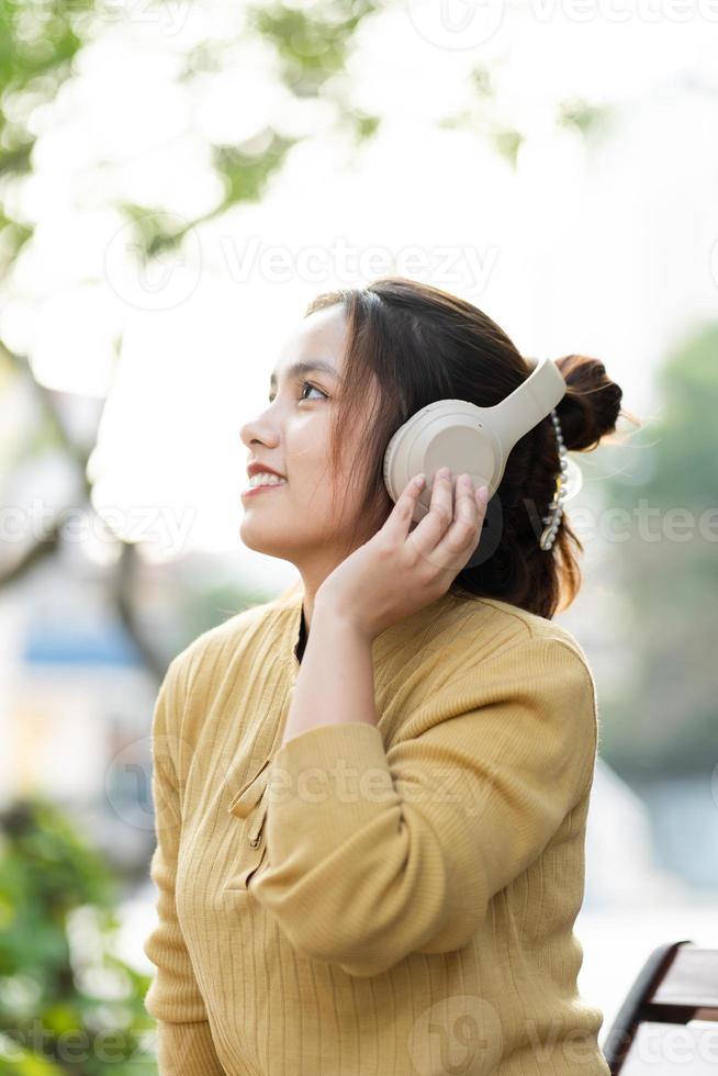 porträtt av ung asiatisk flicka lyssnande till musik i parkera foto