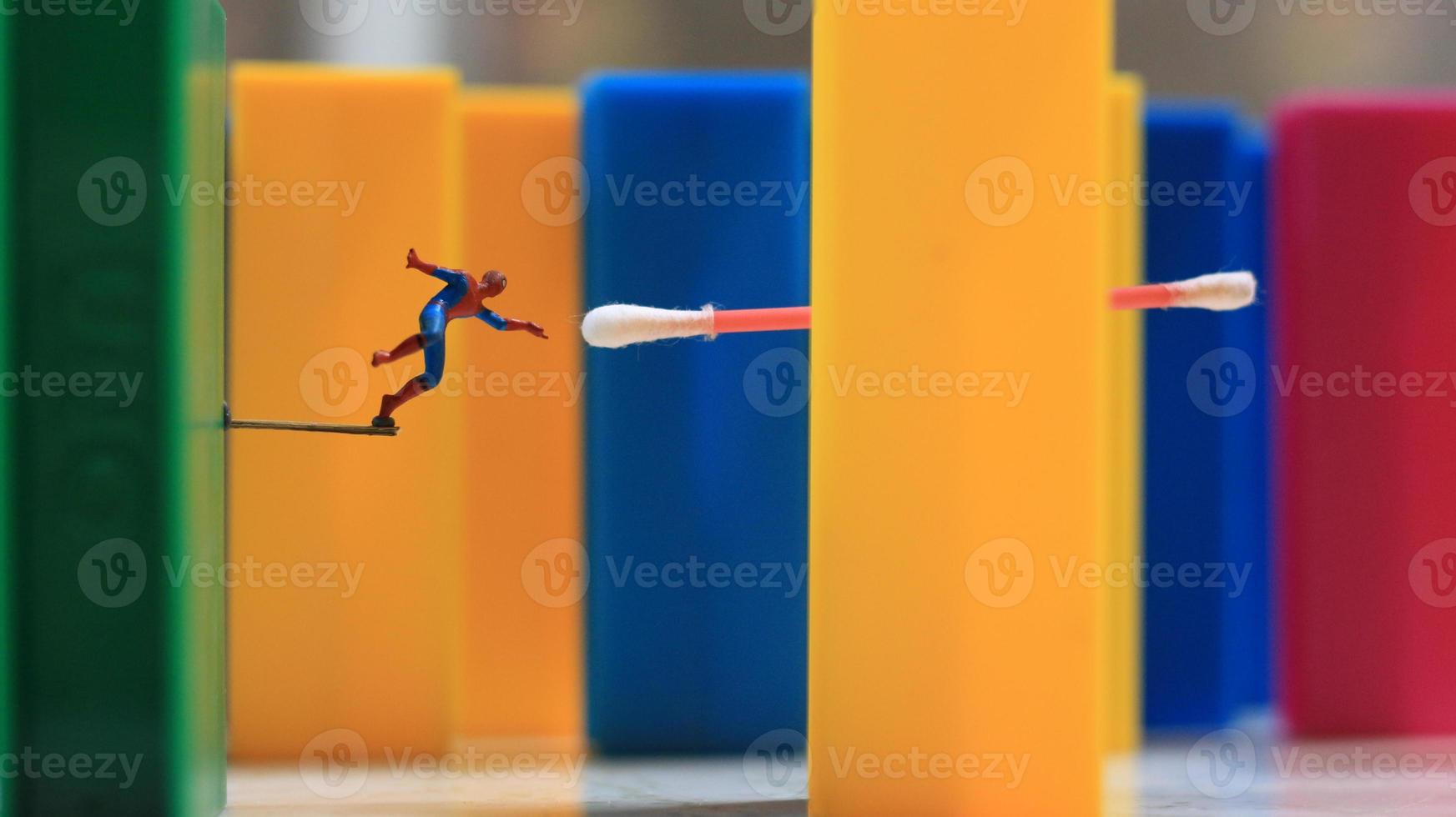 en miniatyr- mänsklig figur med de kraft av en Spindel Hoppar över en färgad blockera leksak. deras begrepp av ombilda superhjältar. foto