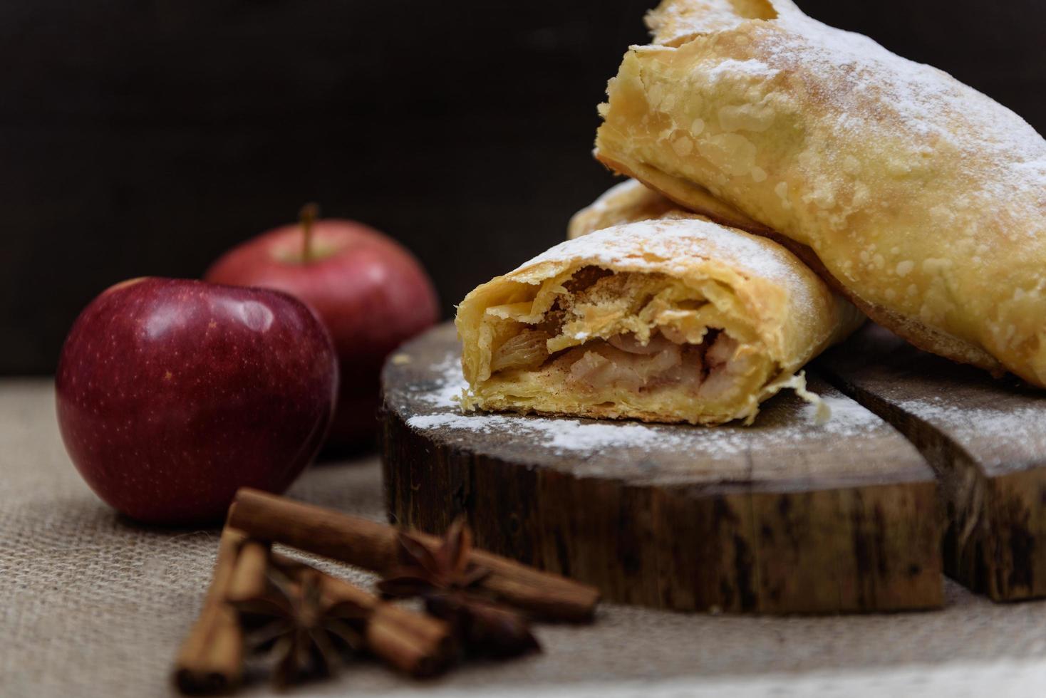 apple strudel på träänden av ett träd med äpplen, kanel och stjärnanis foto