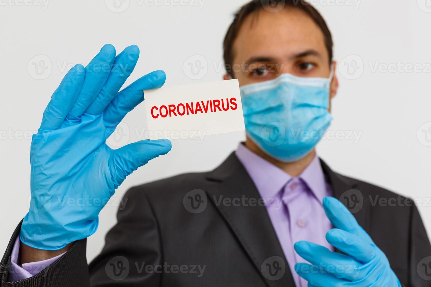 stänga upp av en affärsman i en kostym bär skyddande ansikte mask, skaffa sig redo för coronavirus och pm 2.5 stridande mot grå bakgrund. sjukvård begrepp. foto