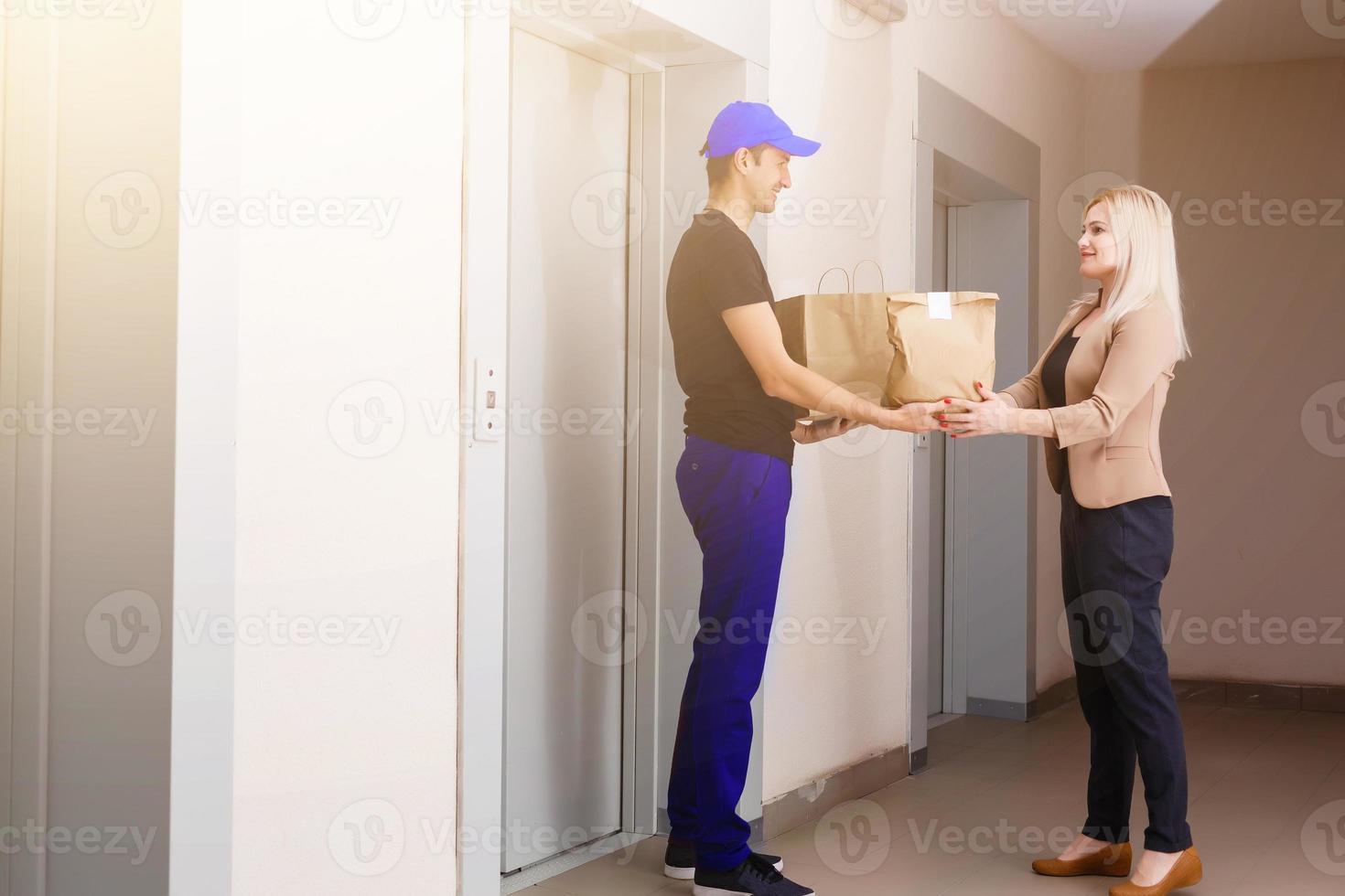 en stilig ung leverans man leverera en paket till lägenhet foto