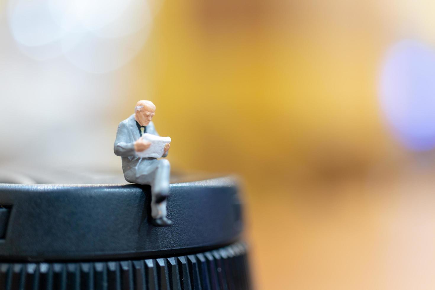 miniatyr affärsman sitter med en färgglad bokeh bakgrund foto