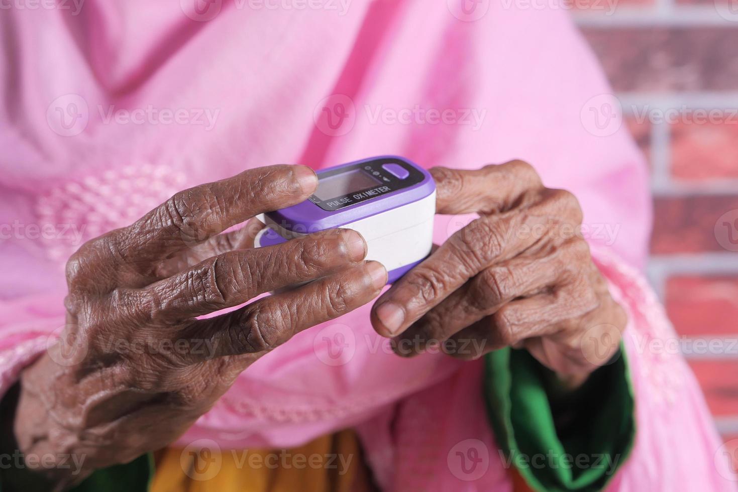 äldre kvinnas hand med pulsoximeter foto