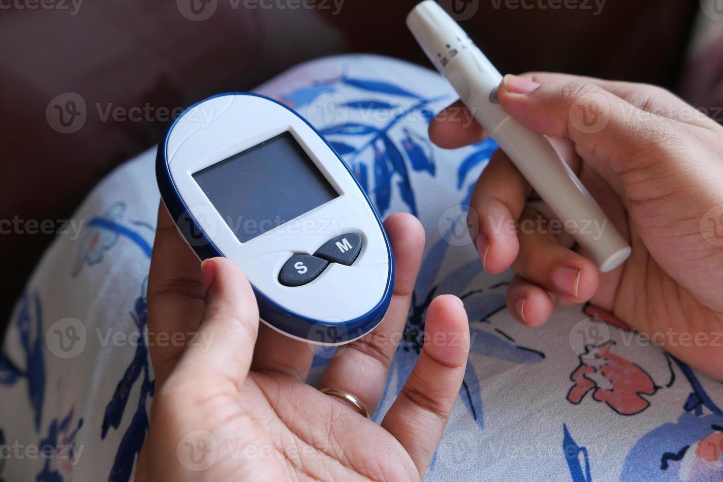 ung kvinna som mäter glukosnivån hemma foto