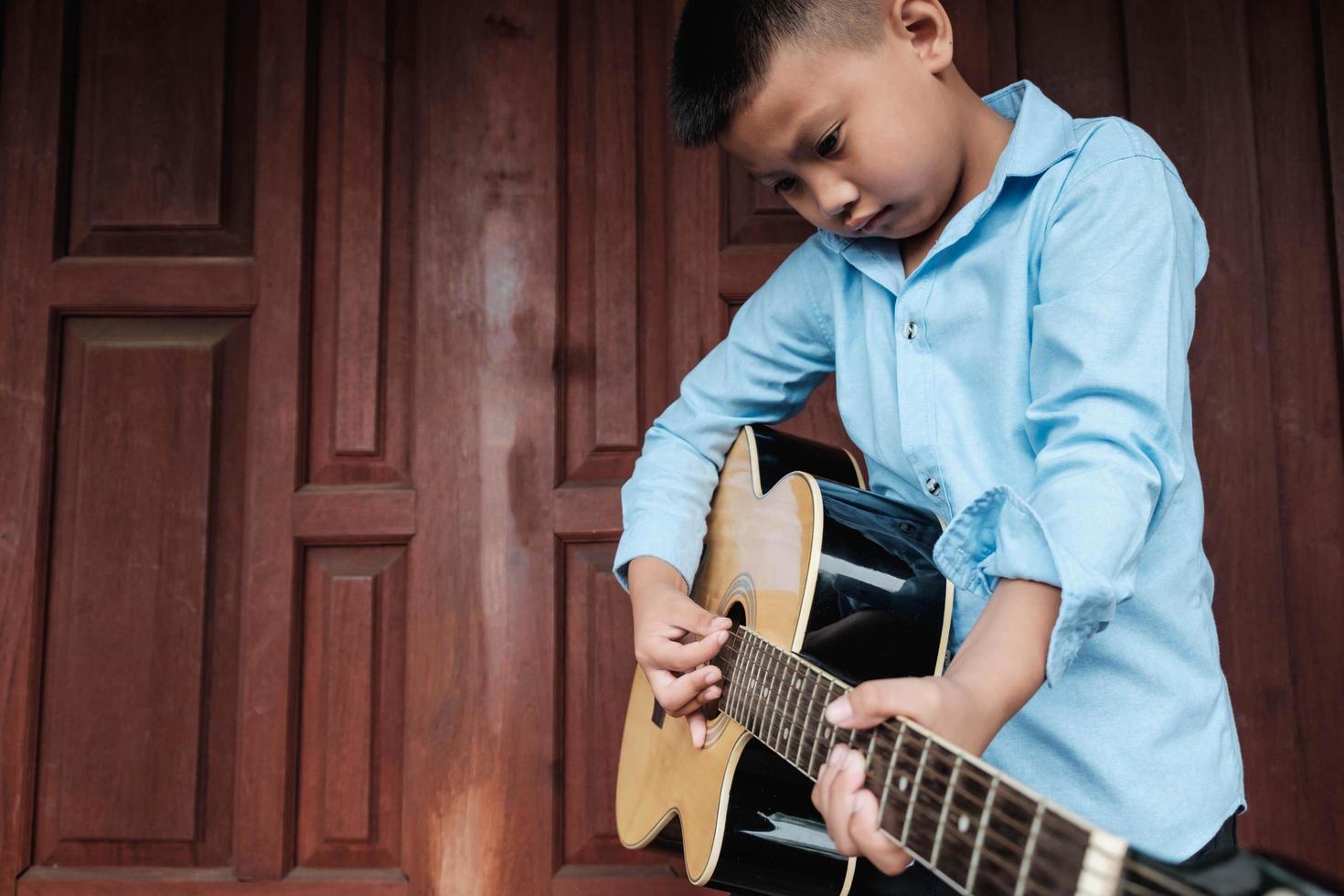 pojke som spelar en akustisk gitarr foto