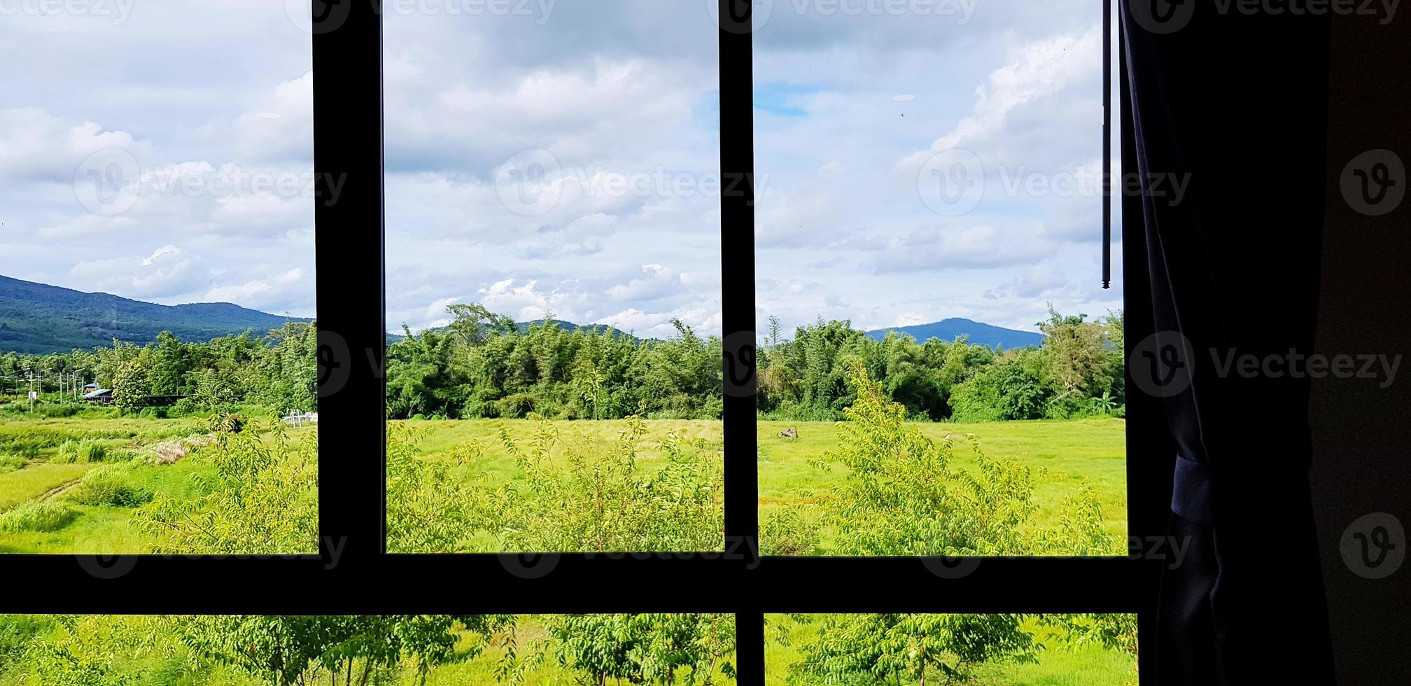 silhuett av linje av fönster och ridå med grön fält, fjäll, blå himmel och moln se. skönhet av natur, landskap och naturlig ram foto