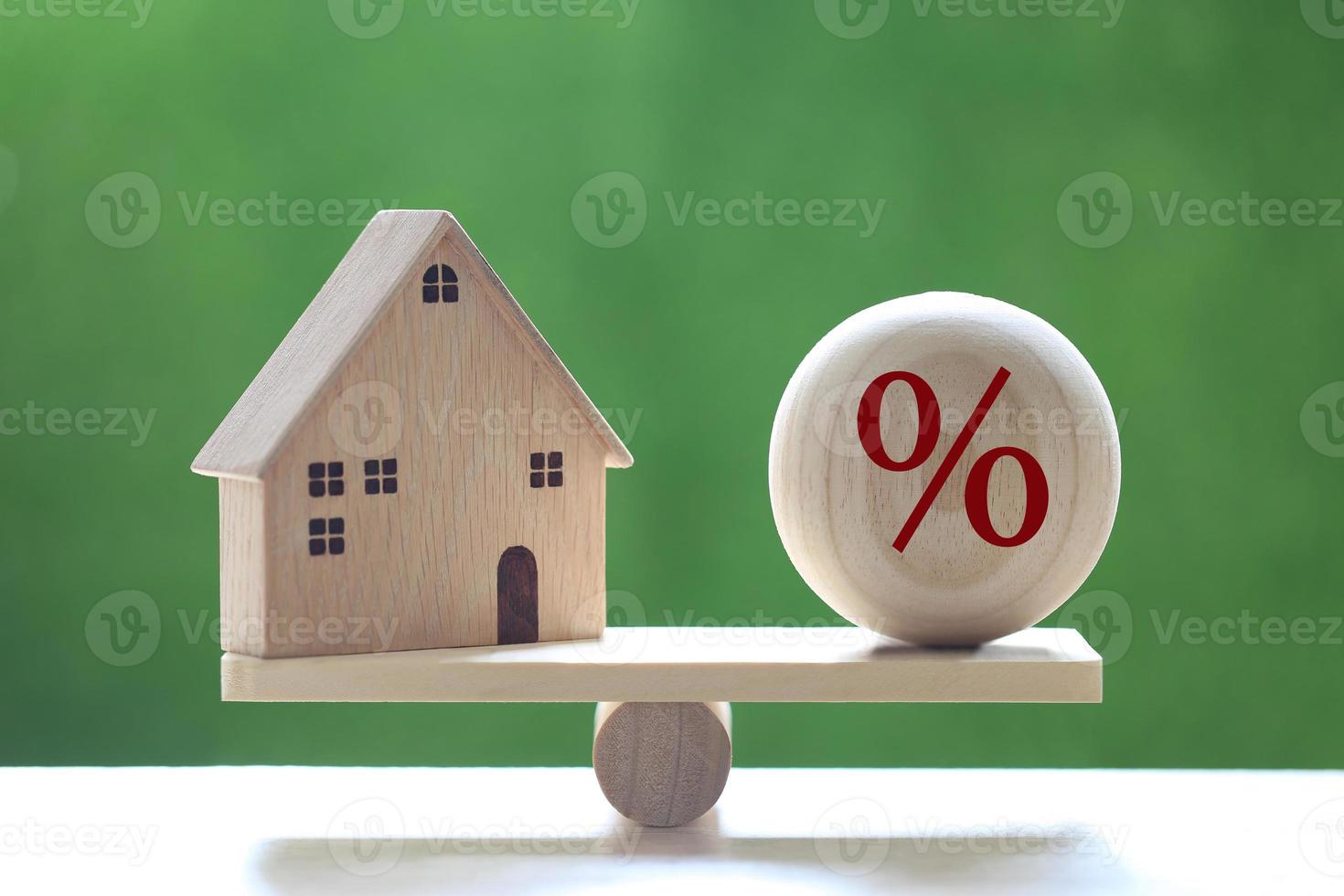 modellhus med en procentuell symbolikon i träskala på en naturlig grön bakgrund, räntesats upp och bankkoncept foto