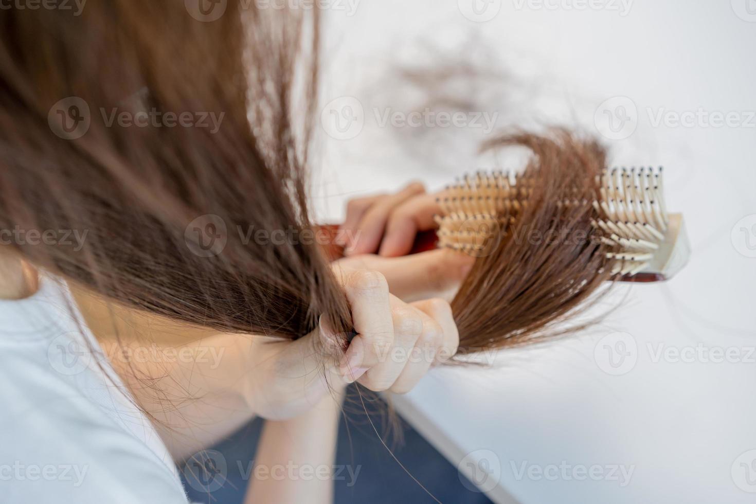 skadad hår, frustrerad asiatisk ung kvinna, flicka hand i innehav borsta delning slutar rörig medan kammande hår, oborstad torr lång hår. hälsa vård skönhet, porträtt isolerat på vit bakgrund. foto