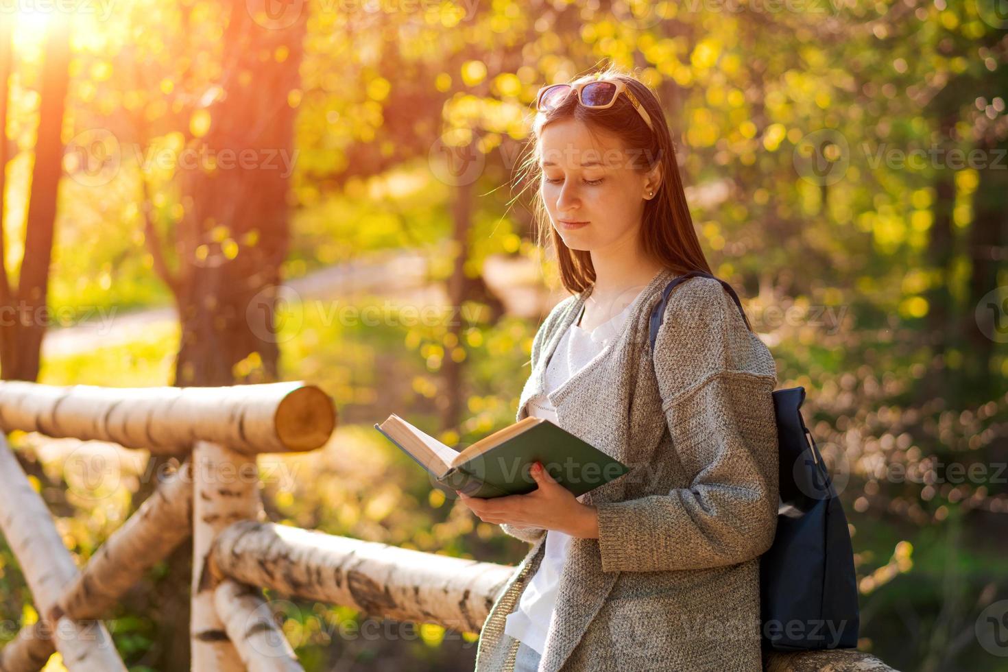 njuter fri tid. Lycklig flicka läsning ett intressant bok i parkera skog foto