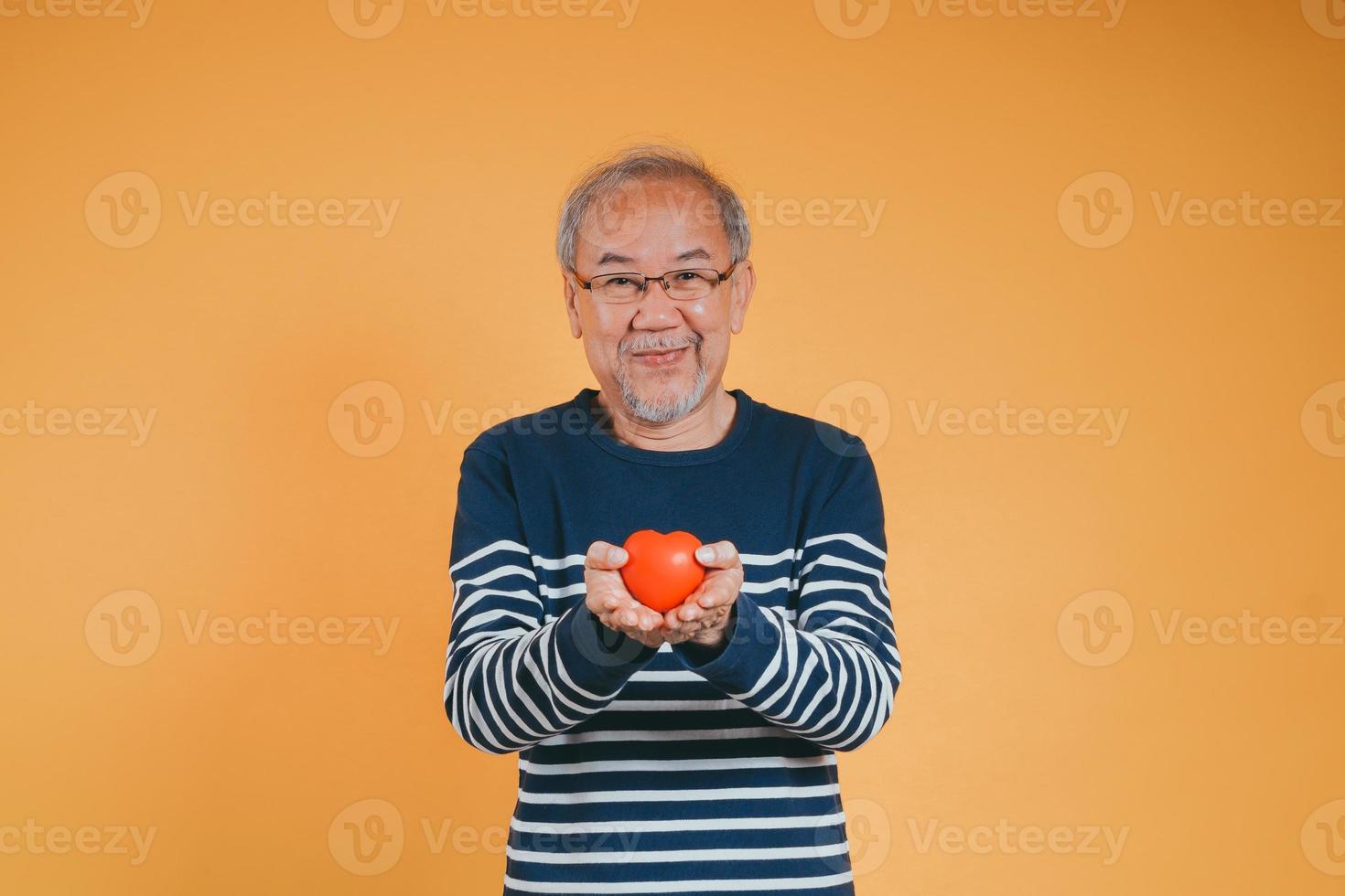 senior manlig innehav hjärta kärlek känsla försäkring begrepp på Färg bakgrund. foto