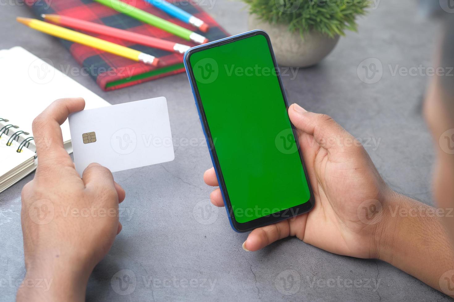 mans hand som håller kreditkort och använder smart telefon för att handla online foto