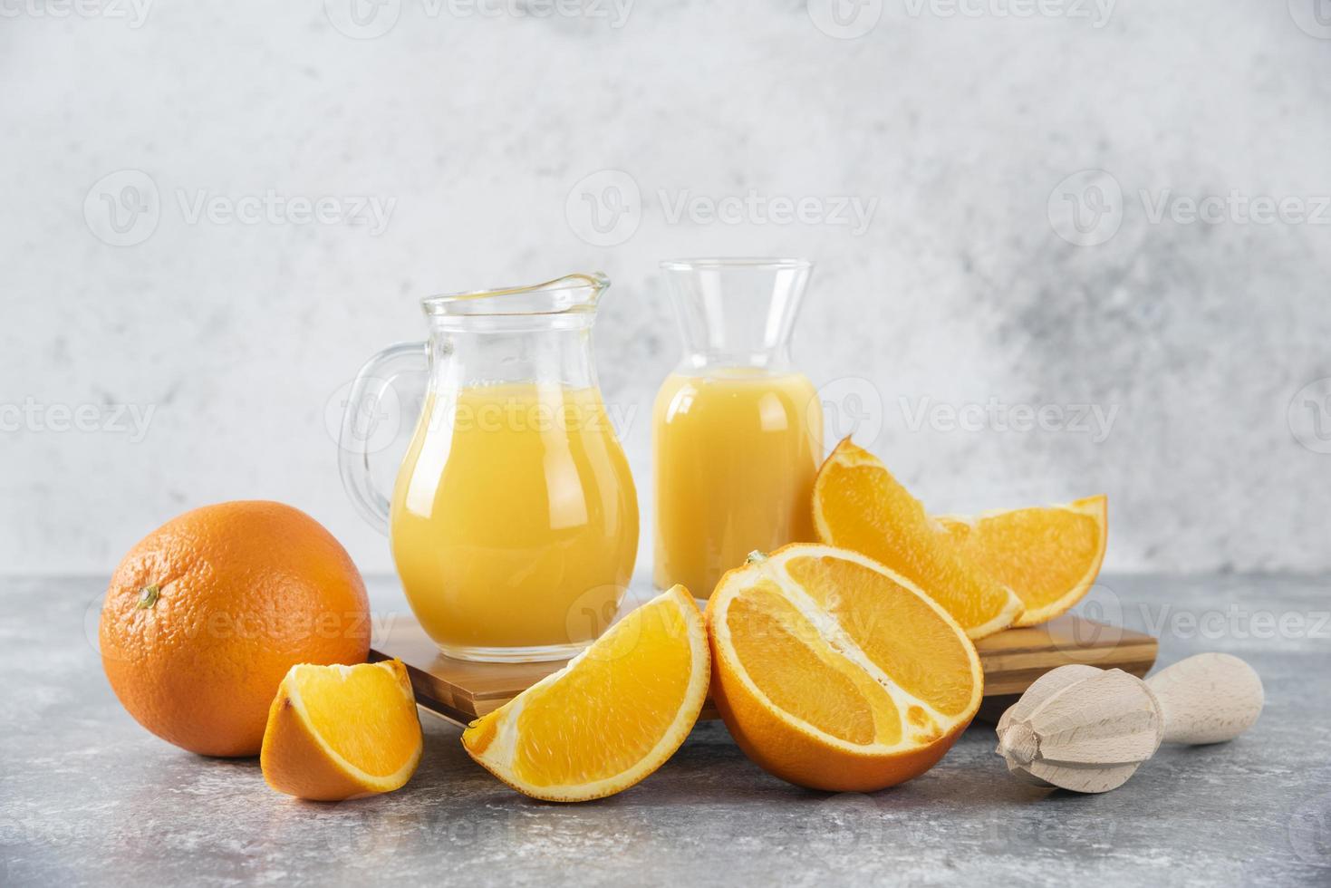 burkar med färsk apelsinjuice och apelsinfrukter på en stenbakgrund foto
