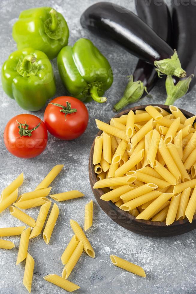 okokt pasta med färska mogna grönsaker placerade på ett stenbord foto