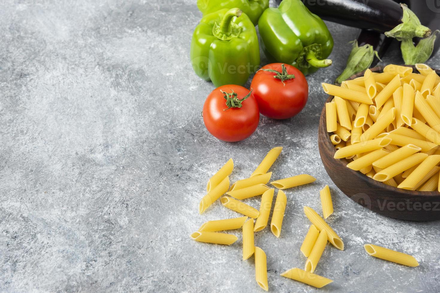 okokt pasta med färska mogna grönsaker placerade på ett stenbord foto