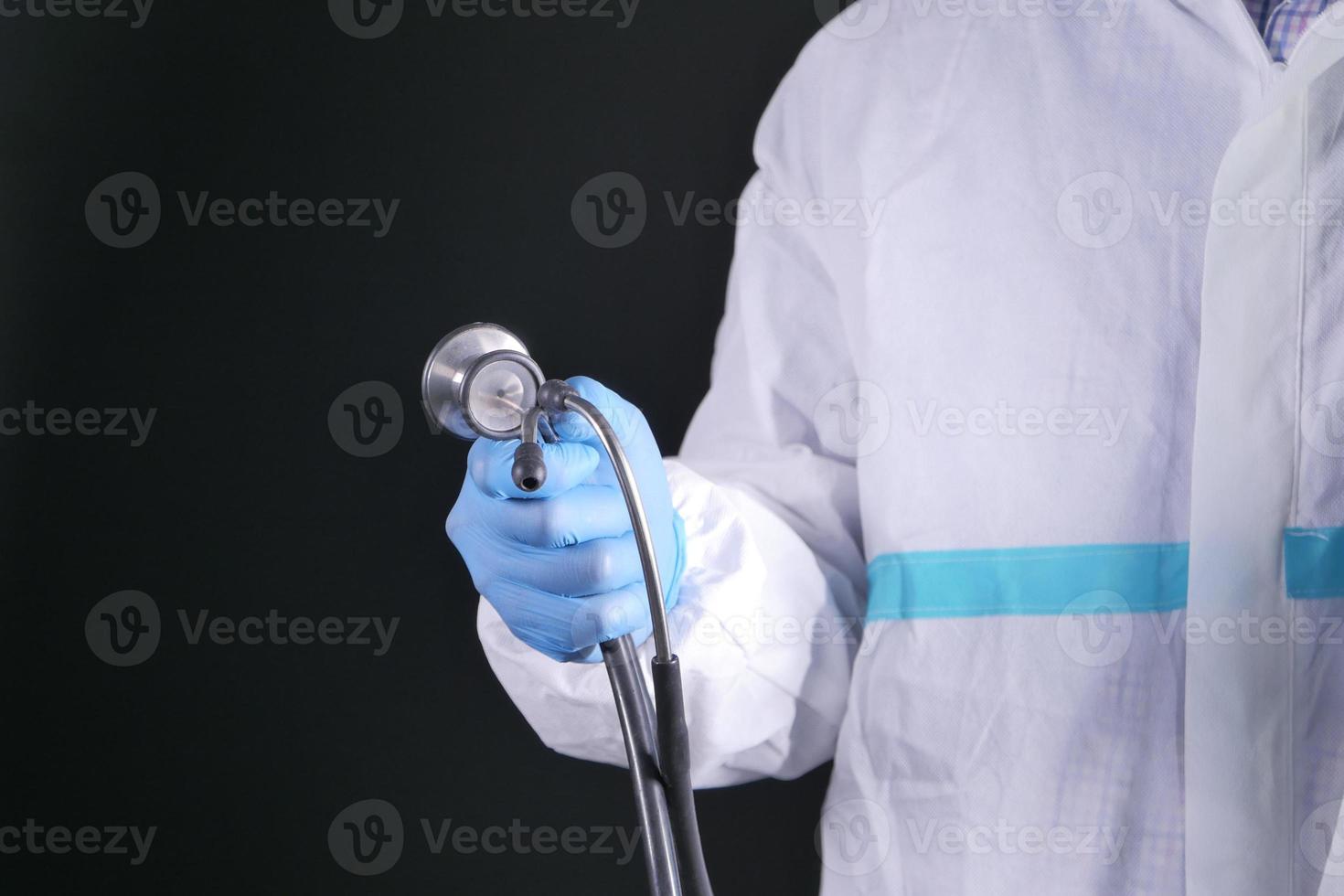 läkarens hand i skyddshandskar som håller stetoskopet foto