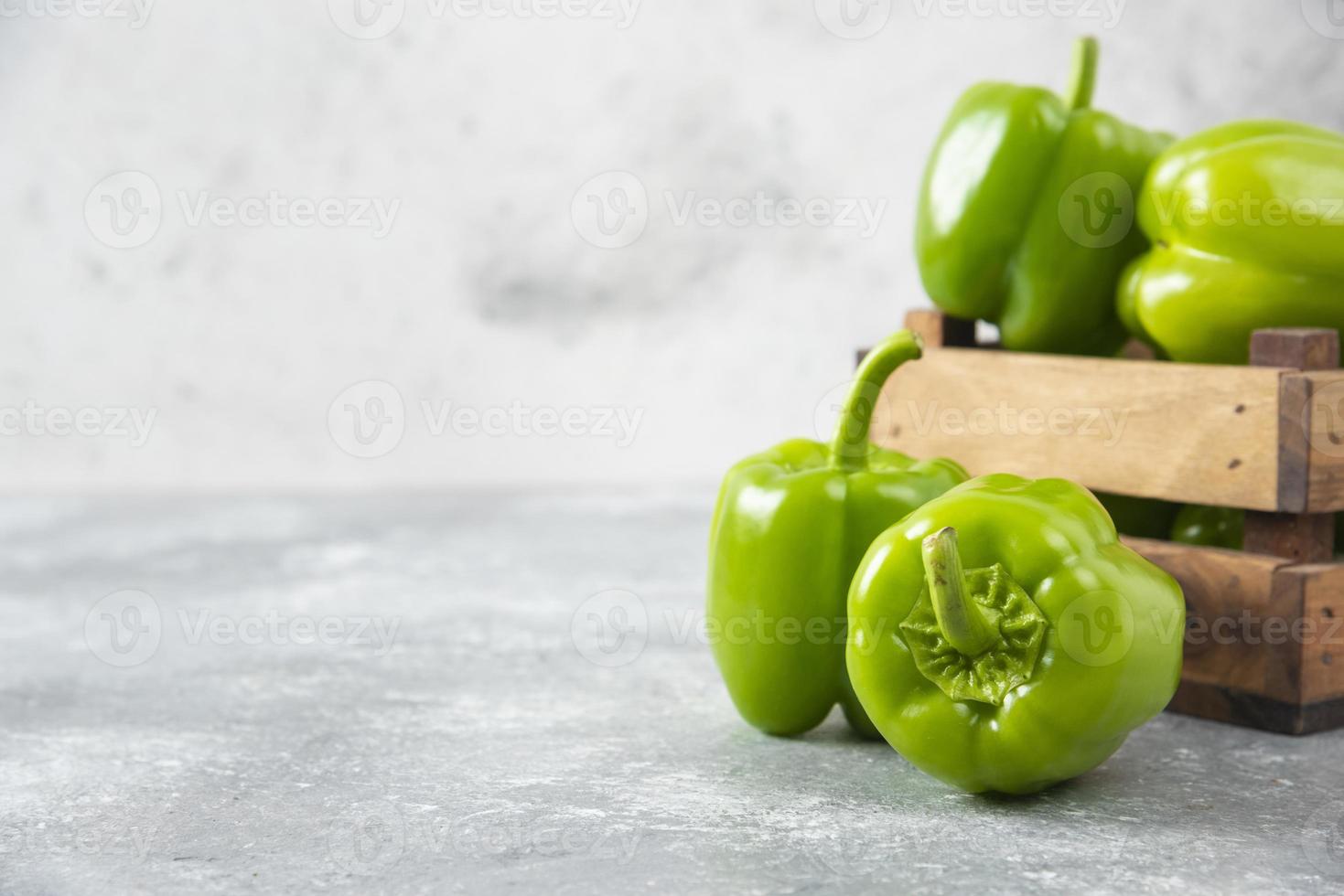 färska gröna paprika placerade i en gammal träask foto