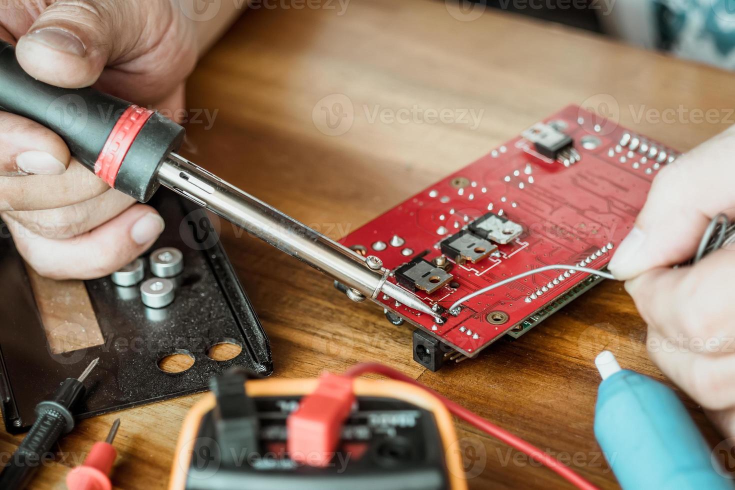 tekniker man innehav järn löda och reparation de krets styrelse förbi lödning. elektrisk arbete begrepp foto